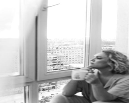 Person taking a break, looking out the window of their apartment
