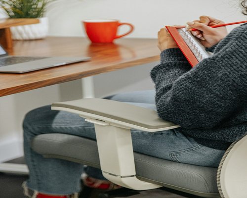 A person taking notes in a bright minimalist home office setup
